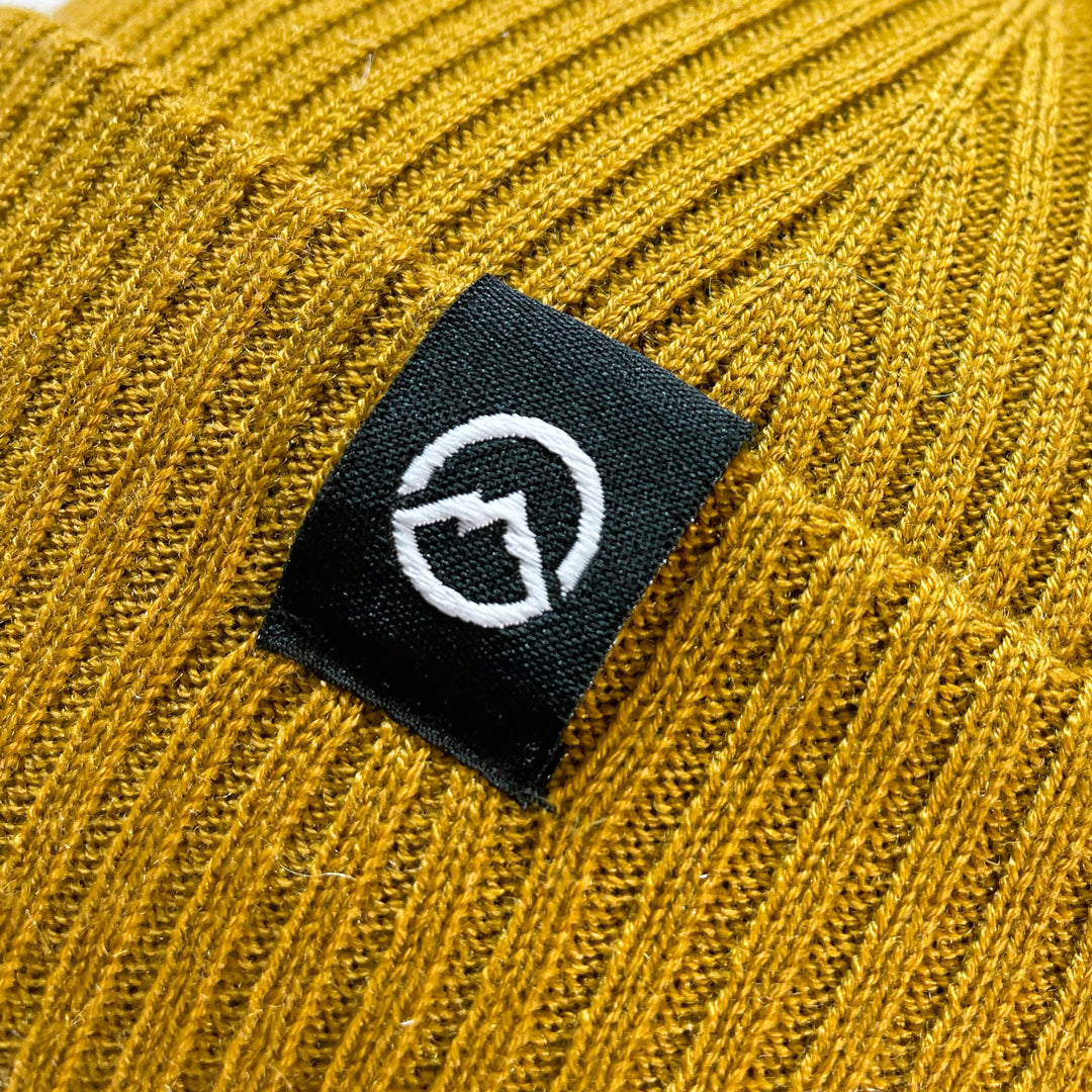Close up of Logo on Domex wool-rich blend fine rib-knit Fisherman's beanie with cuffed hem - Mustard | DOMB1045